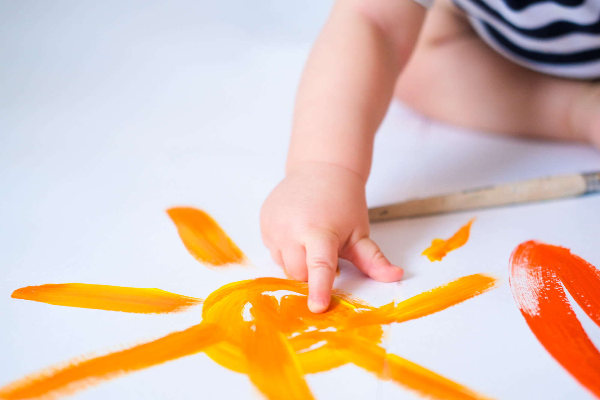 A little finger painting an orange sun