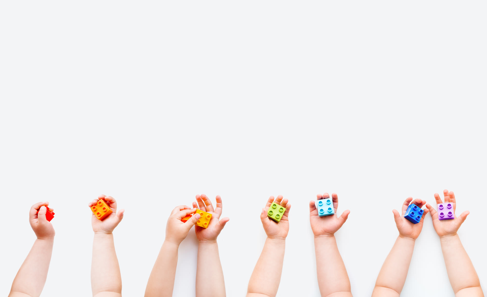 A row of little hands holding up colorful building blocks